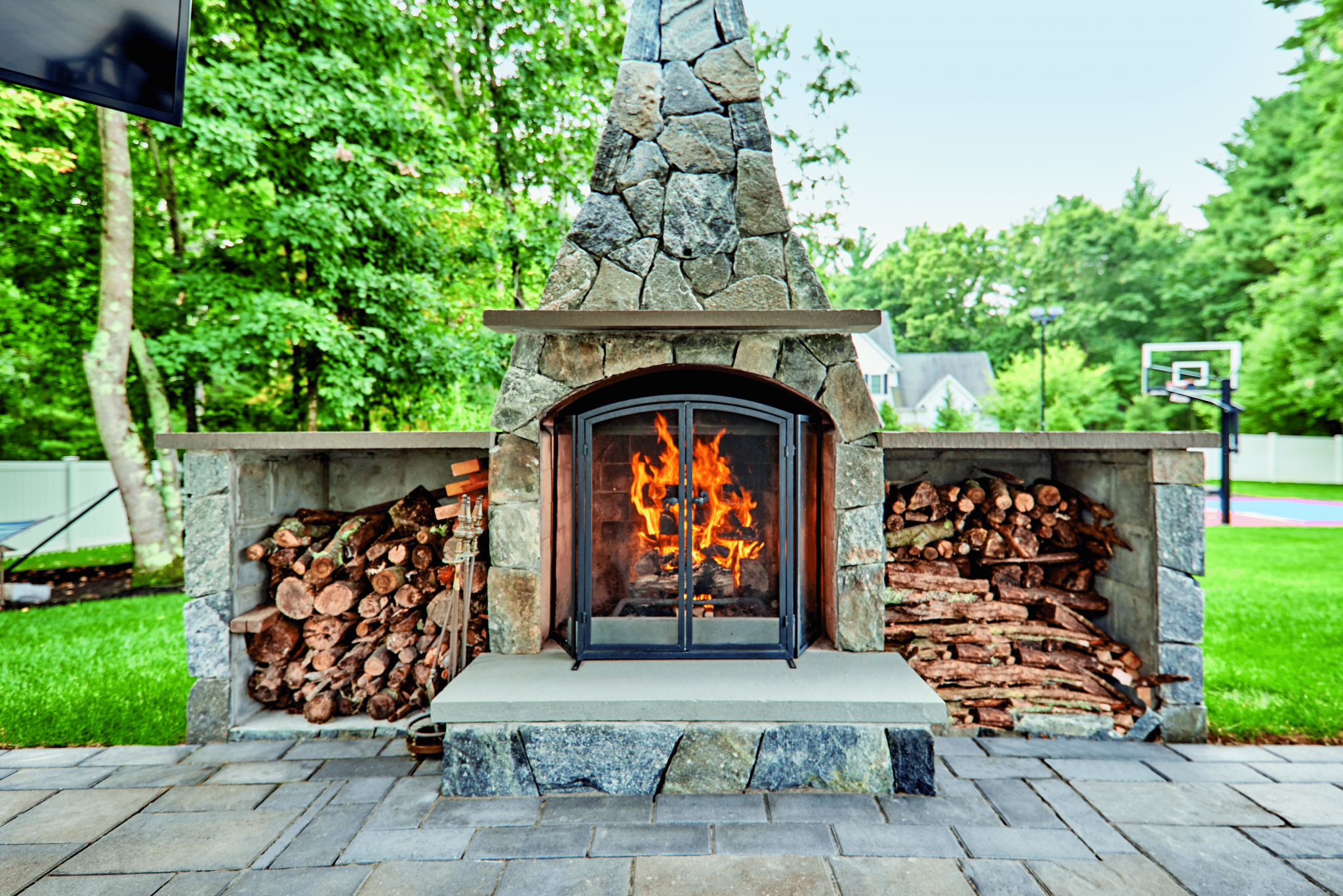 This image depicts an outdoor fireplace with a natural stone patio for a stunning backyard focal point.