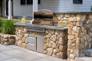 This image depicts an outdoor grill with stunning hardscaping incorporated into the design for a luxurious cooking station.